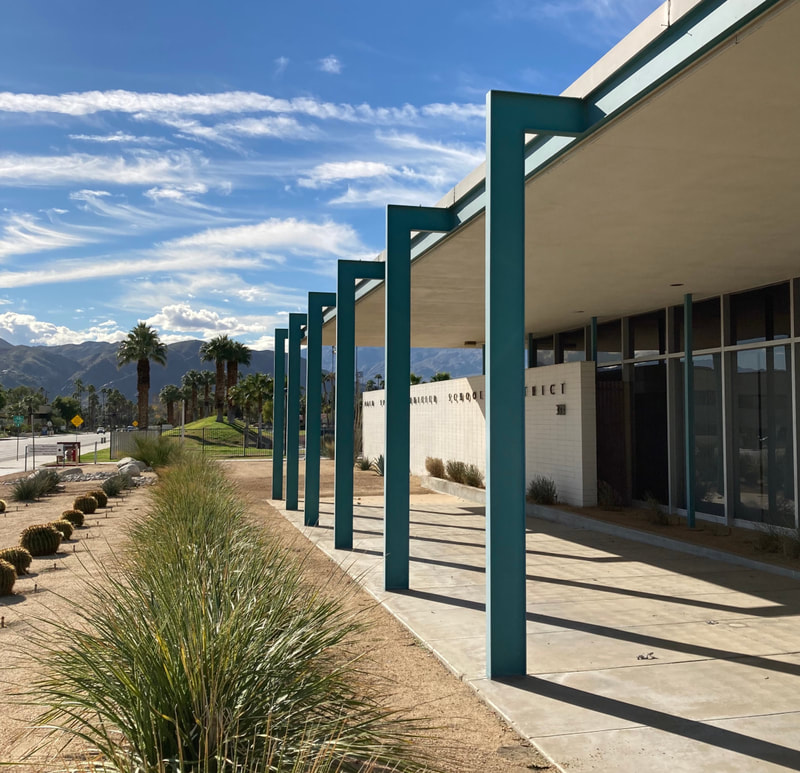 Palm Springs Unified School District building with palm trees, coachella valley mountains, and clouds in the sky